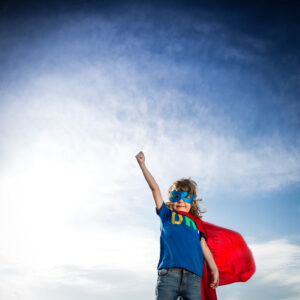 Superhero,kid,against,dramatic,blue,sky,background